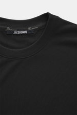 Close-up front top view of the Jacquemus Crew neck T-Shirt 'Rond Carre' black, showing regular fit, mix of paper and microfiber, matte look, logo stitching on side seam, short hem slits, reinforced sleeve cuffs, and loop with logo detail on back.