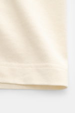 Close-up view of the Jacquemus Crew Neck T-Shirt cream showing pure cotton fabric with soft touch, slim fit, and grosgrain with logo stitching on the chest.
