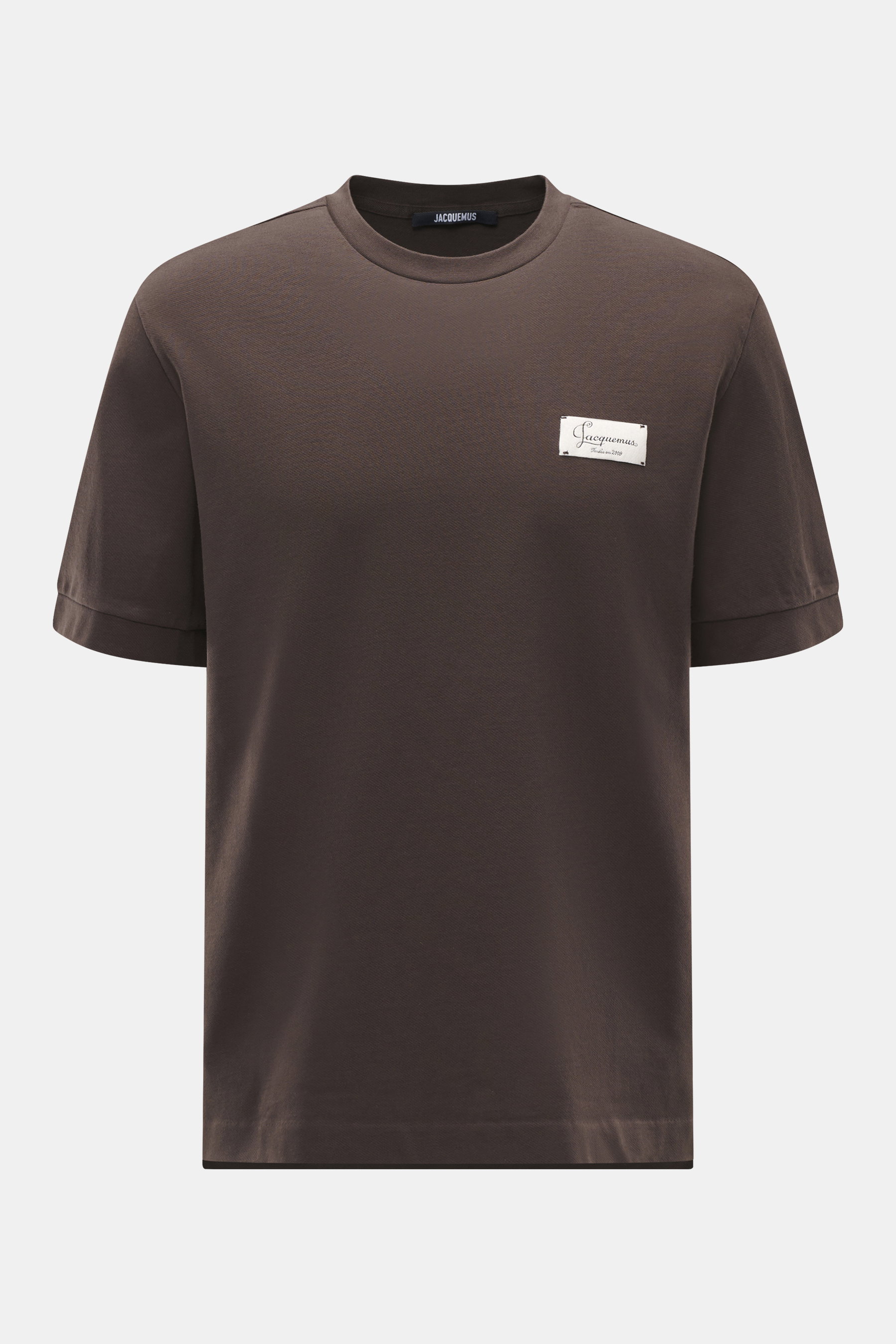 Jacquemus Rundhals-T-Shirt 'Le Montaigne MC' dunkelbraun, Frontansicht, Jersey aus reiner Baumwolle, weicher Griff, feine diagonale Struktur, Slim Fit, Rundhalsausschnitt, Weblabel auf der Brust, seitliche Saumschlitze, verlängerte Rückseite.