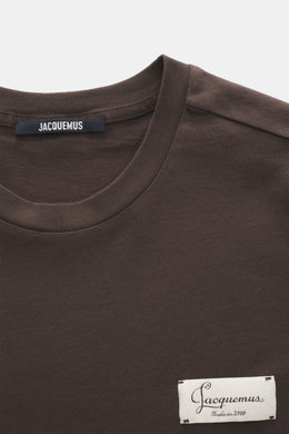 Close-up front view of Jacquemus Crew neck T-shirt 'Le Montaigne MC' dark brown, jersey made of pure cotton, soft touch, fine diagonal texture, slim fit, crew neckline, woven label on chest, side hem slits, extended back.