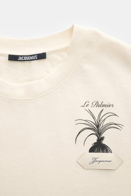 Close-up front view of Jacquemus Crew Neck T-Shirt cream showing neckline and chest with black palm print, grosgrain logo stitching, pure cotton, soft touch, slim fit.