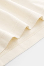 Close-up, angled view of The Row Crew neck T-Shirt 'Maiko' cream, showing pure cotton fabric with fine slubs and soft touch, regular fit, crew neckline.