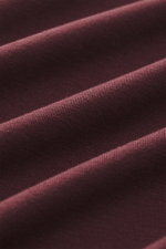 Close-up front perspective of burgundy fabric showing texture and folds, highlighting the Kiefermann Crew neck long sleeve 'Emil' burgundy with jersey in modal and cotton, elasticated fabric, soft touch, slim fit, and crew neck.