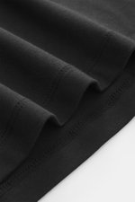 Close-up view of black fabric folds showing fine stitching and texture of the Kiefermann Crew neck long sleeve 'Alberts' black, jersey in modal and cotton, elasticated fabric, soft touch, slim fit, crew neck.