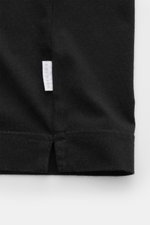 Close-up, front view of the hem and small woven label of the 04651/ A trip in a bag Crew neck T-shirt black, jersey made of pure cotton, soft feel, slim fit, crew neck, small woven label, short hem vents.