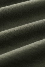 Close-up front view of the soft cotton fabric in grey green of the 04651/ A trip in a bag Crew neck T-Shirt 'Jersey Tee'.

<p>The uncomplicated cotton T-shirt 'Jersey Tee' by 04651/ A TRIP IN A BAG is an indispensable basic from the new season and lets us