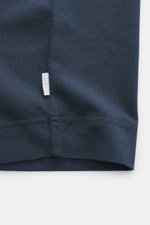 Close-up of the hem and small woven label of the 04651/ A trip in a bag Crew neck T-Shirt navy, showing heavy quality pure cotton fabric with a slightly textured feel, photographed from a side perspective. Durable basic with regular fit and crew neckline.
