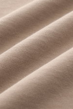 Close-up top-down view of taupe fabric texture showing the heavy cotton jersey of the 04651/ A trip in a bag Crew Neck T-Shirt, pure cotton, heavy quality, slightly textured feel, regular fit, crew neckline, small woven label.