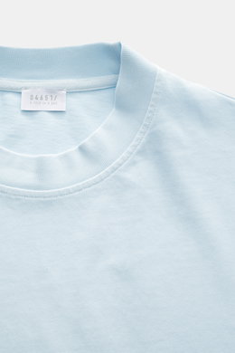 Close-up image from above of the 04651/ A trip in a bag Crew neck T-Shirt pastel blue showing the crew neckline, small woven label, and slightly textured heavy cotton fabric with regular fit. Durable basic for urban everyday life made from pure cotton.