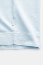 Close-up side view of the hem and small woven label on the 04651/ A trip in a bag Crew neck T-Shirt pastel blue, made from pure heavy cotton jersey with a slightly textured feel, regular fit, and crew neckline. Durable basic perfect for urban everyday lif