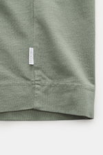 Close-up front view of the hem and small woven label on the 04651/ A trip in a bag Crew neck T-Shirt grey green, showing durable basic pure cotton, heavy quality, slightly textured feel, regular fit, crew neckline. Durable basic: This crew neck T-shirt fr