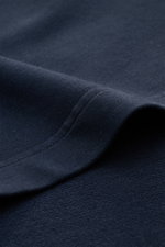 Nahaufnahme des navyfarbenen 04651/ A trip in a bag Rundhals-T-Shirt 'If Tee' aus elastischer Baumwolle mit weichem Griff, schwerer Qualität, Regular Fit und Weblabel, fotografiert aus seitlicher Perspektive.