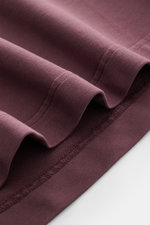Nahaufnahme des Bündchens eines 04651/ A trip in a bag Rundhals-T-Shirts 'If Tee' bordeaux, gezeigt aus seitlicher Perspektive, elastische Baumwolle, weicher Griff, schwere Qualität, Regular Fit, Rundhalsausschnitt, Weblabel in Seitennaht.