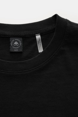 Close-up front view of Moose Knuckles Crew neck T-shirt 'Crescent Tee' black, showing collar and tags; jersey made of pure Pima cotton, soft feel, slim fit, crew neck, signature patch with metal logo on chest, rubberised label print on sleeve, small woven