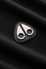Close-up front angle of the Moose Knuckles Crew neck T-shirt 'Crescent Tee' black showing its signature patch with metal logo on soft, pure Pima cotton jersey. Jersey made of pure Pima cotton, soft feel, slim fit, crew neck, rubberised label print on the 