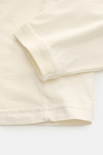 Close-up image of the Stone Island Rundhals-Longsleeve off-white showing the sleeve and hem from a top-down perspective, featuring jersey aus reiner Bio-Baumwolle, weicher Griff, garment dyed, Regular Fit, Rundhalsausschnitt, STONE ISLAND Weblabel auf der