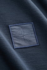 Nahaufnahme des Stone Island Longsleeve 'Ghost Piece' graublau mit tonalem Weblabel auf der Brust, Jersey aus Baumwolle, weicher Griff, Slim Fit, Rundhalsausschnitt.