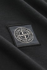 Nahaufnahme des Stone Island Rundhals-Longsleeves schwarz, fotografiert aus seitlicher Perspektive mit Fokus auf das Weblabel auf der Brust.