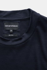 Close-up front view of the Emporio Armani Longsleeve navy collar and label showing pure wool fabric, soft feel, regular fit, and crew neckline.