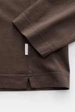 Brown fabric close-up of the 04651/ A trip in a bag Longsleeve 'Jersey Tee' showing sleeve and hem from a top-down perspective. Versatile basic: The lightweight Longsleeve 'Jersey Tee' by 04651/ A TRIP IN A BAG is made of light cotton jersey and is a comf