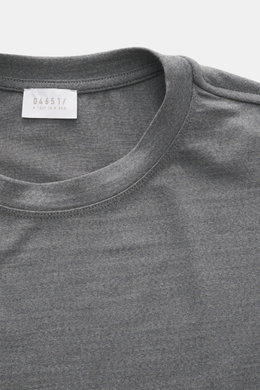 Close-up front view of the grey melange crew neckline and label of the 04651/ A trip in a bag Longsleeve 'WJ Tee', a versatile basic with a mix of wool and microfiber, very soft feel, regular fit, and short hem slits.