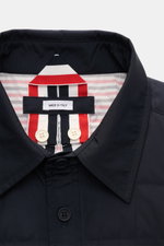 Nahaufnahme der Thom Browne Daunenjacke navy mit Umlegekragen, Knopfleiste, leichter Daunenfüllung und kontrastfarbenem Futter.