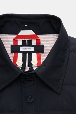Nahaufnahme der Thom Browne Daunenjacke navy mit Umlegekragen, Knopfleiste, leichter Daunenfüllung und kontrastfarbenem Futter.