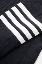 Nahaufnahme der Ärmelpartie der Thom Browne Daunenjacke navy mit leichter Daunenfüllung, klassischer Steppung und markentypischen weißen Streifen.