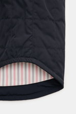 Nahaufnahme der gerundeten Saumkante der Thom Browne Daunenjacke navy mit leichter Daunenfüllung, klassischer Steppung und kontrastfarbenem Innenfutter.