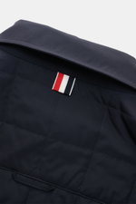 Nahaufnahme der Rückseite der Thom Browne Daunenjacke navy mit leichter Daunenfüllung, klassischer Steppung und markentypischem Streifen.