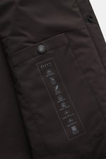 04651/ A trip in a bag Overshirt 'Travel' dunkelbraun, Detailansicht der Innentasche mit Druckknopf und technischen Symbolen, glatte Microfaser, leicht wattiert, wind- und wasserabweisend.