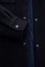 Nahaufnahme aus schräger Perspektive des navy 04651/ A trip in a bag Overshirt 'Wool Overshirt' mit leichter Wattierung, Bouclé aus Microfaser und Wolle, wasserabweisend, Druckknöpfen und Umschlagmanschette.