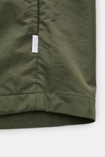 Nahaufnahme der unteren Kante und Naht des olivgrünen 04651/ A trip in a bag Overshirt 'Travel Jacket' aus leichter, schnelltrocknender Microfaser.