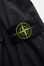 Nahaufnahme des Kompass-Badges am Ärmel des Stone Island Overshirt navy aus elastischer Baumwolle mit weichem Griff, fotografiert von schräg vorne.