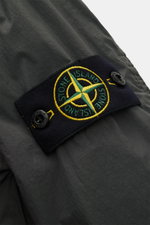 Stone Island Overshirt 'Crinkle Reps' dunkelgrau, Nahaufnahme des typischen Kompass-Badges auf hochwertiger, wind- und wasserabweisender Microfaser.