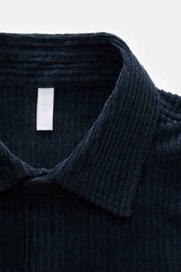 Nahaufnahme des Kent-Kragens des 04651/ A trip in a bag Cord-Overshirt navy, gefertigt aus weichem Breitcord aus Baumwolle mit Stretch-Anteil, garment dyed, oversized Schnitt, Druckknopfleiste, aufgesetzten Brusttaschen in Kontraststoff, Ärmelabschlüssen 