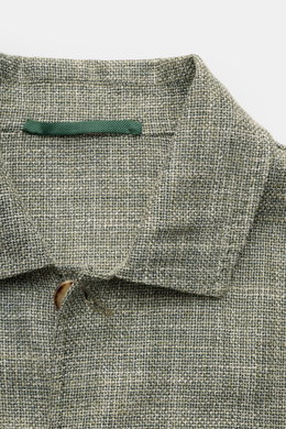 Nahaufnahme des Stile Latino Overshirts 'Gu Texas' dunkelgrün/offwhite meliert mit Umlegekragen, Fünf-Knopf-Leiste und feiner Woll-Seide-Leinen-Mischung, Regular Fit, vier Fronttaschen, Ärmelabschlüssen mit Knopf, unconstructed Design, fotografiert von ob