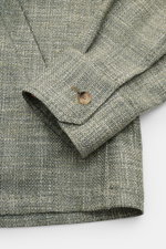 Alt-Tag (124 Zeichen):
Nahaufnahme des Ärmelabschlusses vom Stile Latino Overshirt 'Gu Texas' dunkelgrün/offwhite meliert mit Knopf, Woll-Seide-Leinen-Mix.