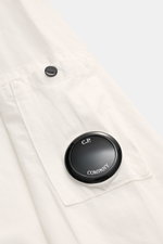 Nahaufnahme des C.P. Company Overshirt offwhite, zeigt aufgesetzte Brusttasche mit Patte und Logodetail am Ärmel, reine Baumwolle.