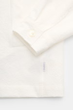 Detailaufnahme des 04651/ A trip in a bag Overshirt 'Technical Seersucker' offwhite von unten mit Slim Fit, Fünf-Knopf-Leiste, Umlegekragen und paspelierten Taschen.