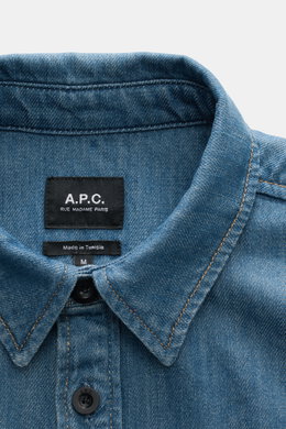 Nahaufnahme des Kragens und der Knopfleiste des A.P.C. Jeans-Overshirts rauchblau aus reiner Baumwolle, Slim Fit, Kent-Kragen, aufgesetzte Brusttaschen, fotografiert von oben. Urbaner Klassiker mit leicht griffiger Denim-Qualität und Sportmanschette.