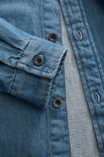 Nahaufnahme des A.P.C. Jeans-Overshirts rauchblau von schräg oben, zeigt Kent-Kragen, Slim Fit, Knopfleiste und Sportmanschette aus reiner Baumwolle Denim.