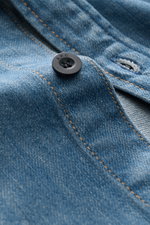 Nahaufnahme aus schräger Perspektive des A.P.C. Jeans-Overshirt rauchblau mit Knopf, Kent-Kragen, Brusttasche und leichter Denim-Baumwollqualität.
