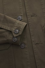 Nahaufnahme des C.P. Company Overshirt khaki von oben, reine Baumwolle, leicht griffig, Slim Fit, glatte Knopfleiste, Umlegekragen, Fronttaschen mit Patte, Ärmel mit Manschette.