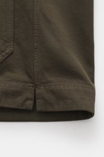 Nahaufnahme des C.P. Company Overshirt khaki von unten, reine Baumwolle, leicht griffig, Slim Fit, glatte Knopfleiste, Umlegekragen, Fronttaschen mit Patte, Ärmelabschlüsse mit Manschette.