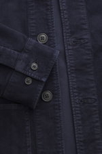 Nahaufnahme des C.P. Company Cord-Overshirt navy von oben, zeigt Slim Fit, Cord aus elastischer Baumwolle, samtiger Griff, garment dyed, Fünf-Knopf-Leiste, Umlegekragen, vier Fronttaschen, Ärmelabschlüsse mit Manschette, Druckknopftasche am Oberarm, label