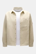 C.P. Company Cord-Overshirt sand in Slim Fit aus elastischem Cord mit Umlegekragen, Brusttasche, Manschetten, Druckknopftasche, frontal fotografiert.