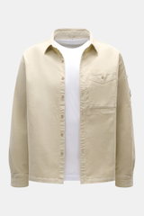 C.P. Company Cord-Overshirt sand in Slim Fit aus elastischem Cord mit Umlegekragen, Brusttasche, Manschetten, Druckknopftasche, frontal fotografiert.