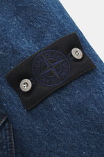 Close-up view of the compass badge on the upper arm of the Stone Island Blue denim jacket, showing denim made of pure cotton with typical material texture, slim fit, two-way zipper, turn-down collar, and patch chest pocket.