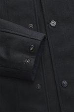 Nahaufnahme aus schräger Perspektive des Stone Island Overshirt 'Ghost Piece' navy mit Slim Fit, Fünf-Knopf-Leiste, Umlegekragen, tonalem Badge, weichem Griff, Schurwolle und Microfaser, Ärmelabschlüssen mit Knopf und einer Innentasche.